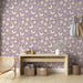 Une pièce lumineuse avec un papier peint floral mauve orné de papillons et de marguerites, créant une ambiance douce et printanière.
