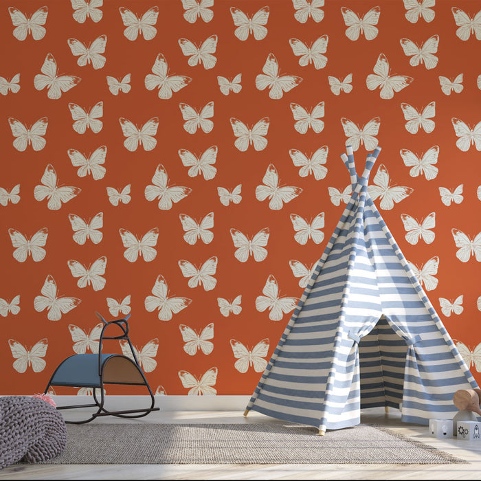 Une chambre d'enfant avec un papier peint orange orné de motifs de papillons blancs, créant une ambiance joyeuse et ludique.
