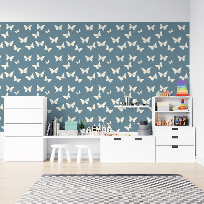 Une chambre d'enfant avec un papier peint bleu profond orné de motifs de papillons blancs, créant une atmosphère douce et joyeuse.