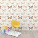 Une chambre d'enfant avec un papier peint représentant des papillons dans des teintes douces de beige et de brun sur fond clair, créant une atmosphère légère et joyeuse.