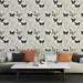 Un salon élégant avec un papier peint floral représentant des papillons noirs et des feuillages délicats sur fond beige, créant une atmosphère douce et apaisante.