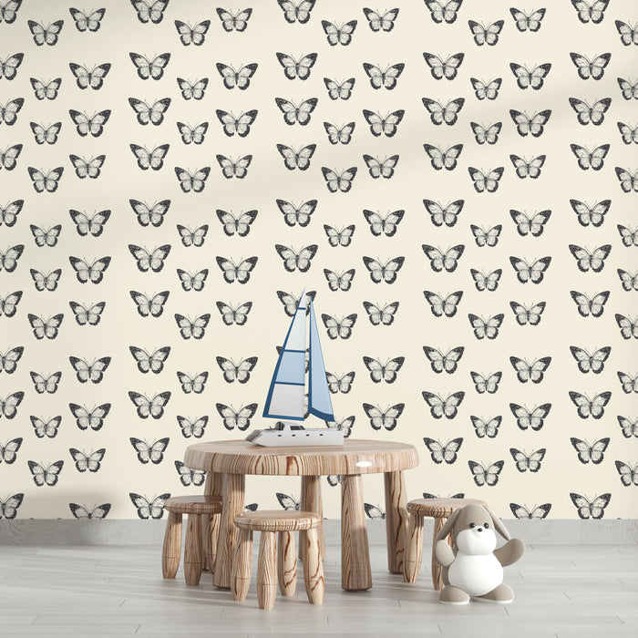 Une chambre d'enfant avec un papier peint crème orné de motifs de papillons noirs, créant une atmosphère douce et ludique.