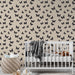 Une chambre d'enfant avec un papier peint beige orné de motifs de papillons noirs, créant une atmosphère douce et poétique.