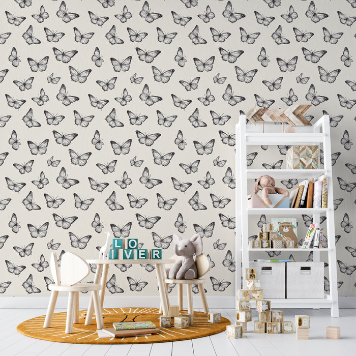 Une chambre d'enfant avec un papier peint beige orné de motifs de papillons noirs, créant une atmosphère douce et ludique.