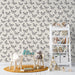 Une chambre d'enfant avec un papier peint beige orné de motifs de papillons noirs, créant une atmosphère douce et ludique.