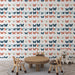 Une chambre d'enfant avec un papier peint aux motifs de papillons colorés dans des teintes douces de bleu, corail et crème, créant une atmosphère joyeuse et ludique.