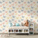 Une chambre enfantine avec un papier peint aux motifs de papillons colorés dans des teintes pastel, créant une ambiance douce et joyeuse.