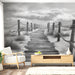 Une pièce moderne avec un papier peint en noir et blanc représentant un chemin en bois menant à la plage, créant une atmosphère apaisante et contemplative.
