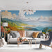 Un salon lumineux avec un papier peint illustrant un paysage côtier coloré, mêlant des teintes de vert, orange et bleu, créant une atmosphère apaisante et naturelle.