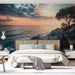 Une chambre moderne avec un papier peint représentant un paysage côtier au coucher de soleil, évoquant une atmosphère apaisante et naturelle.