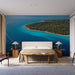 Une chambre moderne avec un papier peint représentant une vue aérienne d'une île entourée d'eaux turquoise, créant une atmosphère apaisante et naturelle.