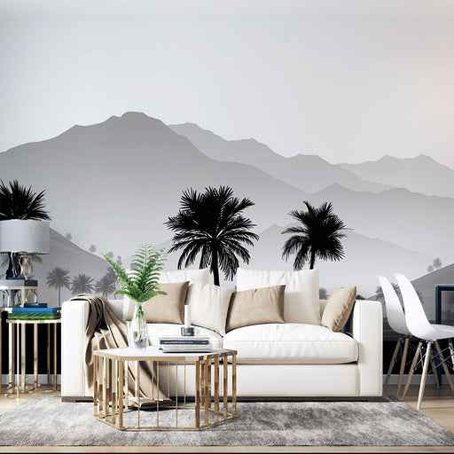 Un salon élégant avec un papier peint représentant des montagnes en dégradé de gris et des palmiers noirs, créant une ambiance apaisante et moderne.