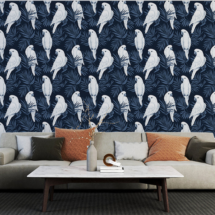 Un salon moderne avec un papier peint tropical bleu marine illustrant des perroquets blancs entourés de feuillages, créant une ambiance vivante et exotique.
