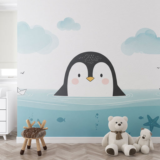 Une chambre d'enfant avec un papier peint ludique représentant un pingouin souriant émergeant de l'eau, dans des teintes douces de bleu et de blanc.