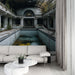 Un salon contemporain avec un papier peint représentant une piscine abandonnée, aux teintes froides et mélancoliques, évoquant une atmosphère nostalgique et mystérieuse.