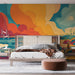 Une chambre contemporaine avec un papier peint abstrait aux teintes vives d'orange, bleu et jaune, évoquant une atmosphère chaleureuse et dynamique.