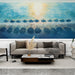 Un salon moderne avec un papier peint aquarelle représentant des parasols sur la plage, aux teintes bleu et doré évoquant une ambiance estivale et relaxante.