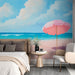 Une chambre moderne avec un papier peint représentant une plage ensoleillée, un parasol rose et des teintes apaisantes de bleu et de rose.