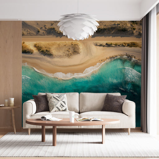 Une pièce lumineuse avec un papier peint représentant une vue aérienne d'une plage, mêlant des teintes de sable et d'eau turquoise, créant une ambiance relaxante et estivale.