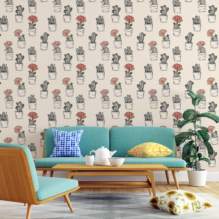 Un salon lumineux avec un papier peint illustrant des pots de plantes succulentes en noir et blanc, rehaussés de touches de couleur corail, créant une ambiance fraîche et accueillante.