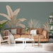 Un salon moderne avec un papier peint tropical vert doux orné de grandes feuilles dorées, créant une atmosphère chaleureuse et apaisante.