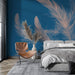 Une chambre moderne avec un papier peint bleu profond orné de grandes plumes rose pâle, créant une atmosphère élégante et apaisante.