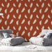 Un salon moderne avec un papier peint terracotta orné de plumes blanches créant une atmosphère chaleureuse et accueillante.