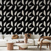 Un salon moderne avec un papier peint noir orné de plumes blanches délicates, créant une atmosphère élégante et apaisante.