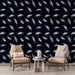 Un salon élégant avec un papier peint noir orné de plumes blanches délicates, créant une atmosphère apaisante et sophistiquée.