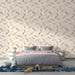 Une chambre apaisante avec un papier peint aux motifs de plumes délicates dans des teintes douces de rose et beige sur fond clair.