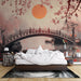 Une chambre apaisante avec un papier peint représentant un paysage asiatique, un pont en bois et un soleil orangé, créant une atmosphère sereine et romantique.