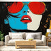 Papier peint pop art visage féminin stylisé avec lunettes rouges et arrière-plan coloré pour salon moderne.