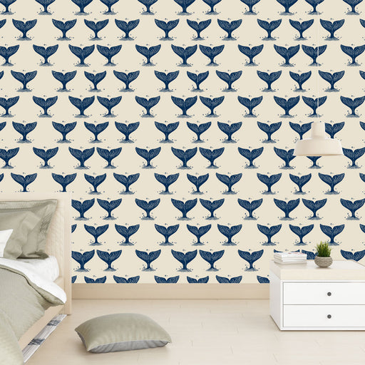 Une chambre lumineuse avec un papier peint illustrant des queues de baleines stylisées en bleu sur fond crème, créant une ambiance marine et apaisante.