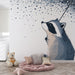 Une chambre d'enfant avec un papier peint illustrant un raton laveur contemplatif sous un ciel étoilé, créant une ambiance douce et rêveuse.