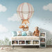 Une chambre d'enfant avec un papier peint illustrant un renard mignon dans un ballon dirigeable sur un fond bleu ciel, créant une ambiance ludique et rêveuse.