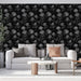 Un salon moderne avec un papier peint noir orné de roses blanches délicates, créant une atmosphère élégante et romantique.