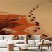 Un salon contemporain avec un papier peint représentant des empreintes de pas sur une plage aux teintes ocres et rouges, évoquant une atmosphère chaleureuse et méditative.