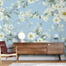 Une pièce moderne avec un papier peint floral sur fond bleu clair, orné de grandes fleurs blanches et de feuilles vertes, créant une ambiance fraîche et apaisante.