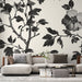 Un salon contemporain avec un papier peint floral noir et blanc représentant des branches et des fleurs, créant une ambiance élégante et artistique.