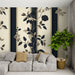 Une pièce de salon avec un papier peint floral aux motifs élégants de fleurs et feuillages sur fond crème, rehaussé de bandes verticales sombres, créant une ambiance raffinée et chaleureuse.