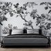 Une chambre moderne avec un papier peint floral noir et blanc représentant des branches et des fleurs, créant une ambiance élégante et artistique.