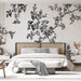 Une chambre élégante avec un papier peint floral noir et blanc présentant des branches délicates et des fleurs, créant une ambiance artistique et apaisante.