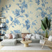Un salon élégant avec un papier peint floral bleu sur fond crème, créant une atmosphère douce et apaisante, idéale pour la détente.