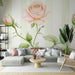 Un salon lumineux avec un papier peint floral représentant une grande rose pastel sur fond vert clair, créant une atmosphère douce et apaisante.