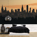 Une chambre contemporaine avec un papier peint représentant une silhouette urbaine noire sur fond dégradé orange, créant une ambiance moderne et chaleureuse.