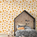 Une chambre d'enfant avec un papier peint joyeux représentant des soleils et des nuages souriants dans des teintes chaudes, créant une ambiance ludique et chaleureuse.