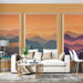 Un salon moderne avec un papier peint représentant des montagnes aux dégradés orange et bleu, créant une atmosphère chaleureuse et apaisante.