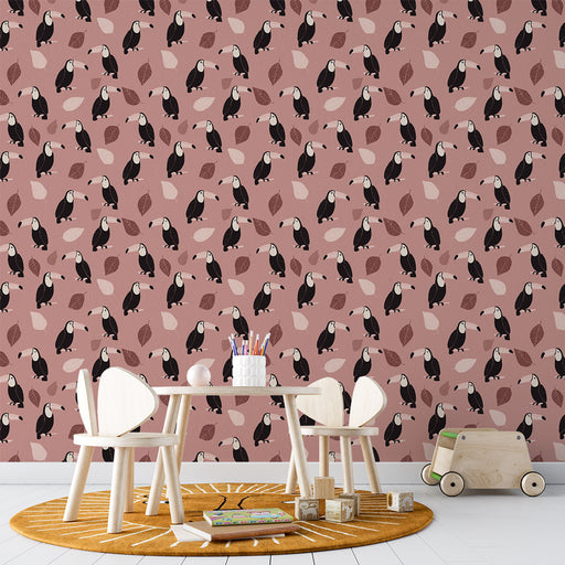 Une salle de jeux lumineuse avec un papier peint ludique représentant des toucans noirs et des feuilles sur fond rose, créant une ambiance joyeuse et accueillante.