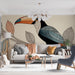 Un salon moderne avec un papier peint illustrant un toucan coloré sur fond beige, créant une ambiance tropicale et artistique.
