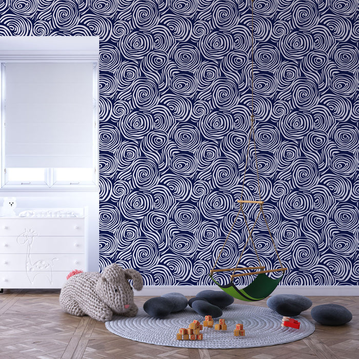 Une chambre enfantine avec un papier peint bleu marine orné de motifs spirales blanches, créant une ambiance dynamique et ludique.